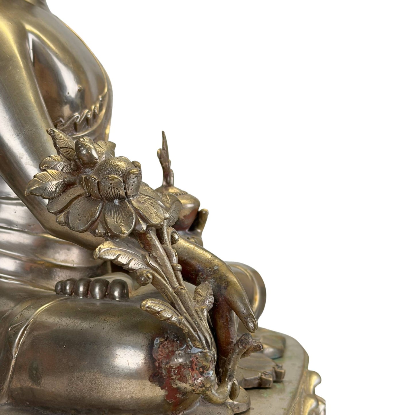 Detail van de rijk uitgewerkte utpala-lotus en medicijnplant van een antieke Newar Bhaisajyaguru in verzilverd brons, met originele rituele gebruikssporen en natuurlijke patina.